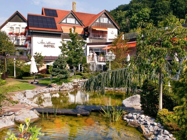Ringhotel Teutoburger Wald****, Tecklenburg Brochterbeck Ringhotel Teutoburger Wald: Ein gepflegter Garten mit Teich und Brücke vor einem Hotelgebäude.
