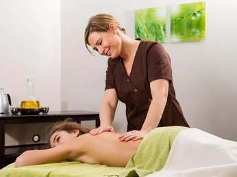Massage im Ringhotel Teutoburger Wald in Tecklenburg Brochterbeck Eine Masseurin massiert den Rücken einer entspannten Person in einem wohligen SPA-Ambiente.