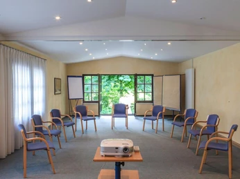 Landhotel Der Schwallenhof: Tagung Ein lichtdurchfluteter Tagungsraum mit gemütlichen Stühlen, Beamer und einer grünen Aussicht.