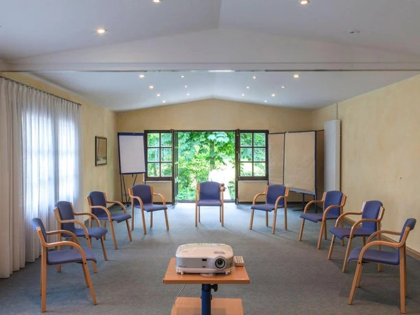 Landhotel Der Schwallenhof: Tagung Ein lichtdurchfluteter Tagungsraum mit gemütlichen Stühlen, Beamer und einer grünen Aussicht.