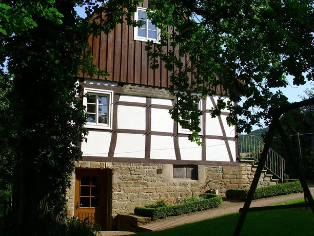 Die Bauernhofpension Lüdekingshof präsentiert eine Fachwerkfassade mit Sprossenfenstern im Grünen.