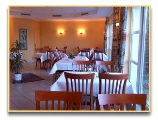Ein helles, freundlich eingerichtetes Restaurant mit Holzmöbeln und weißen Tischdecken.