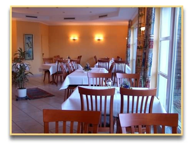 Ein helles, freundlich eingerichtetes Restaurant mit Holzmöbeln und weißen Tischdecken.