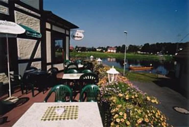 Terrasse mit grünen Stühlen, Tischen und Sonnenschirm und Weserblick