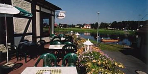Terrasse mit grünen Stühlen, Tischen und Sonnenschirm und Weserblick