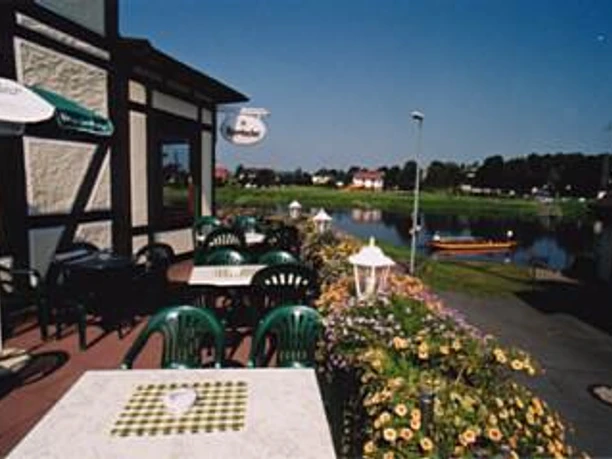 Terrasse mit grünen Stühlen, Tischen und Sonnenschirm und Weserblick