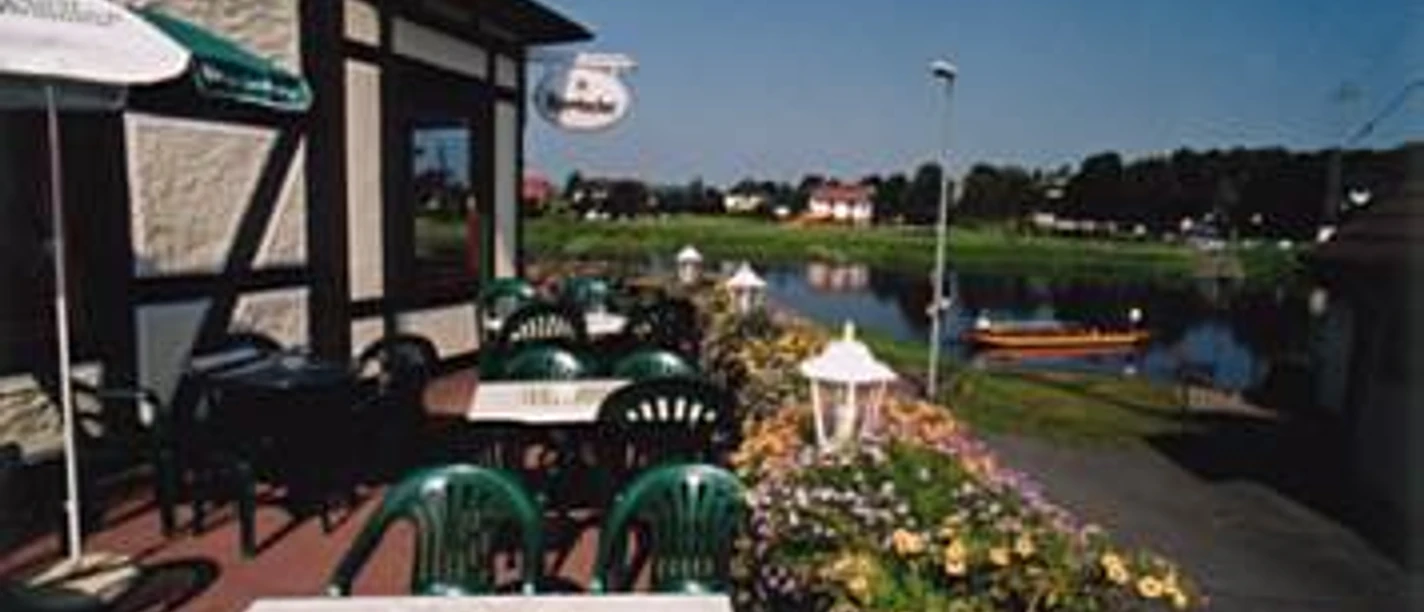 Veranda mit Weserblick Terrasse mit grünen Stühlen, Tischen und Sonnenschirm und Weserblick