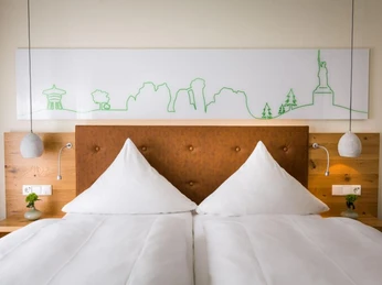 Ganz der Teuto - Zimmer im Hotel Sandebeck Modernes Hotelzimmer mit Doppelbett, beleuchtet von eleganten Nachttischlampen und stilvollem Wandbild.