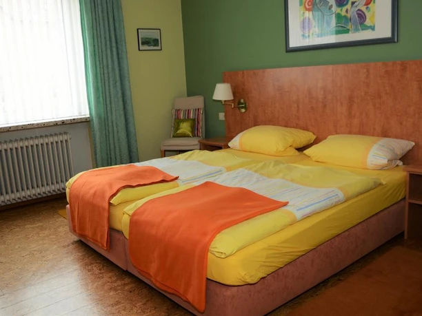 Zweibettzimmer im Hotel Mertens mit hellen Farben, zwei bequemen Betten und gemütlicher Dekoration.