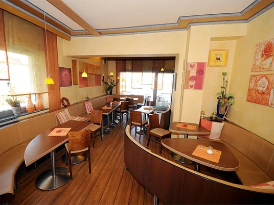 Cafe/Bäckerei Pension Mertens Einladendes Café mit warmem Interieur und freundlicher Atmosphäre, Tische für bis zu vier Personen.