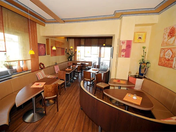 Cafe/Bäckerei Pension Mertens Einladendes Café mit warmem Interieur und freundlicher Atmosphäre, Tische für bis zu vier Personen.