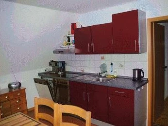 Küchenzeile Moderne Küchenzeile mit roten Schränken, Spüle, Arbeitsplatte und Geräten in einer hellen Umgebung.