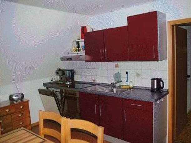 Küchenzeile Moderne Küchenzeile mit roten Schränken, Spüle, Arbeitsplatte und Geräten in einer hellen Umgebung.