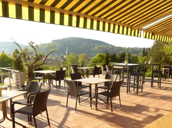 Die Terrasse des Hotel Sonnenhof bietet Sitzgelegenheiten mit Blick auf eine grüne Hügellandschaft.