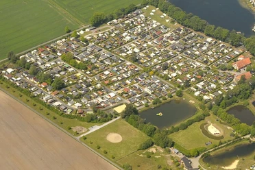 Camp zur Rotbuche Luftaufnahme eines großen Campingplatzes mit Wohnmobilen, umgeben von Wald und zwei kleinen Seen.
