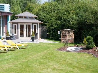 Grüner Außenbereich der Driburger Therme mit Liegestühlen, Gartenhaus und Insektenhotel.