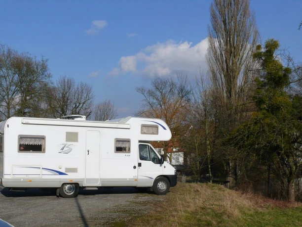 Wohnmobilstellplatz am Klunsberg Nieheim Wohnmobil auf einem Parkplatz am Klunsberg in Nieheim, umgeben von Bäumen und freiem Himmel.