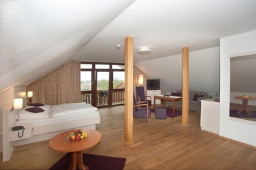 Landhotel Annelie - Studio 2 Ein geräumiges Studio mit Holzboden, Sitzbereich, Doppelbett und Fenstern, das Licht hereinlässt.