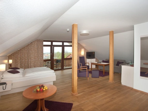 Landhotel Annelie - Studio 2 Ein geräumiges Studio mit Holzboden, Sitzbereich, Doppelbett und Fenstern, das Licht hereinlässt.