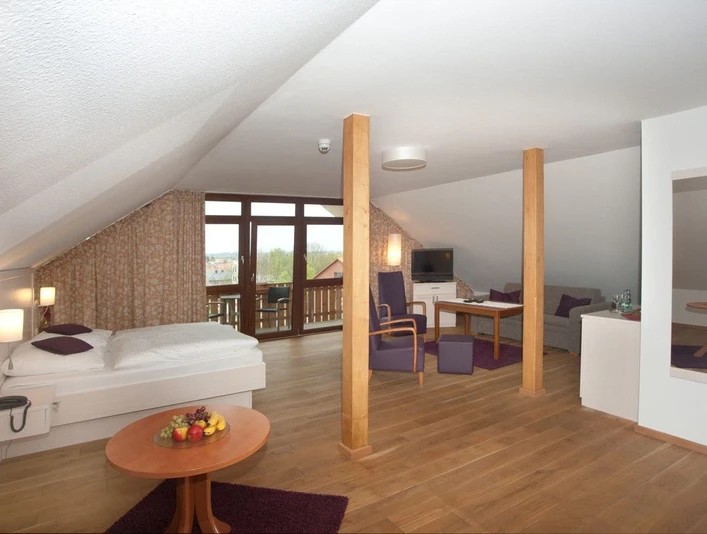 Landhotel Annelie - Studio 2 Ein geräumiges Studio mit Holzboden, Sitzbereich, Doppelbett und Fenstern, das Licht hereinlässt.