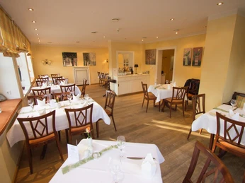Restaurant, Landgasthof Potthoff, Borgholzhausen-Barnhausen Ein einladendes Restaurant mit hellen Wänden, eleganten Holzmöbeln und weiß gedeckten Tischen.