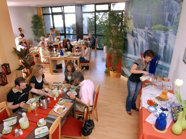 Frühstücksraum mit Gästen, die an Tischen sitzen, reichhaltiges Frühstücksbuffet