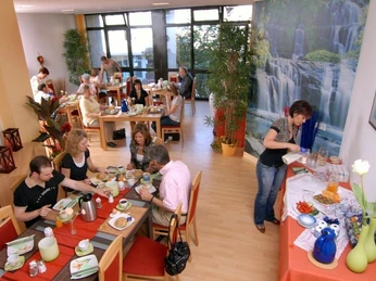 Frühstücksoase Frühstücksraum mit Gästen, die an Tischen sitzen, reichhaltiges Frühstücksbuffet