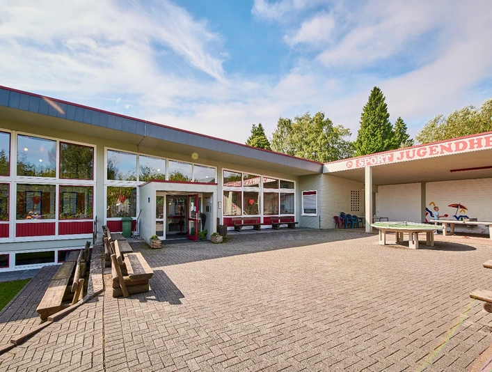 Aussenansicht Jugendherberge Bad Driburg Jugendherberge Bad Driburg mit Sonnenterrasse, Picknicktischen und großen Fenstern in modernem Design.