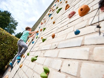 Kletterwand Jugendherberge Bad Driburg Ein Junge erklimmt eine Kletterwand mit bunten Griffen an der Jugendherberge Bad Driburg.