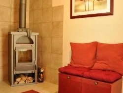 Warmer Eingangsbereich mit rotem Teppich, einem Kaminofen und Sitzbank mit roten Kissen.