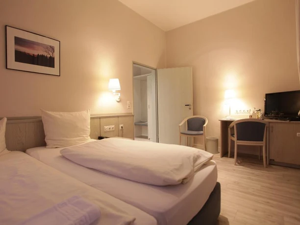 Zimmeransicht Landhaus Schieder Helles, modern eingerichtetes Doppelzimmer mit zwei Einzelbetten, Schreibtisch, TV und Wandlampe.