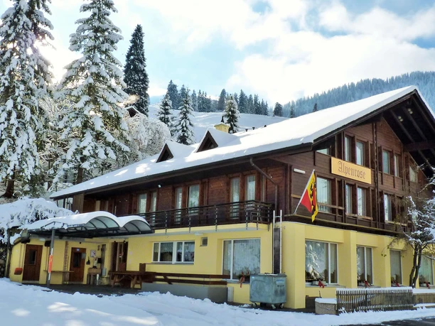 Grand chalet en bois recouvert de neige, aux murs jaunes