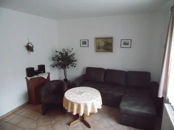 Ferienhof Meyer Sitzecke Eine gemütliche Sitzecke mit Ecksofa und rundem Tisch, sanft beleuchtet und geschmackvoll dekoriert.