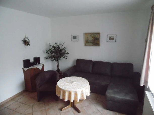 Ferienhof Meyer Sitzecke Eine gemütliche Sitzecke mit Ecksofa und rundem Tisch, sanft beleuchtet und geschmackvoll dekoriert.