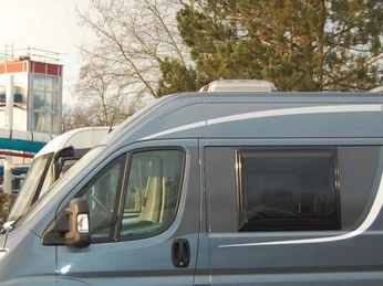 Das Hallenbad ist direkt nebenan Wohnmobil-Parkplatz vor einem Erlebnisbad mit bunten Wasserrutschen und karger Wintervegetation.