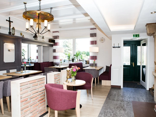 hilckmann-107 Ein stilvolles Café mit modernen Möbeln, Holzakzenten und großen Fenstern, das Licht und Wärme ausstrahlt.