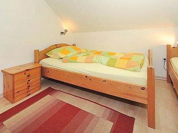 haren-kizi-c_nst_6775_kl Zwei Einzelbetten mit farbiger Bettwäsche, Holzkommode und Teppich in einem hellen Schlafzimmer