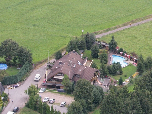 Eifgen-Sauna Luftaufnahme eines Landgasthofs mit Swimmingpool, umgeben von Bäumen und Grünflächen.