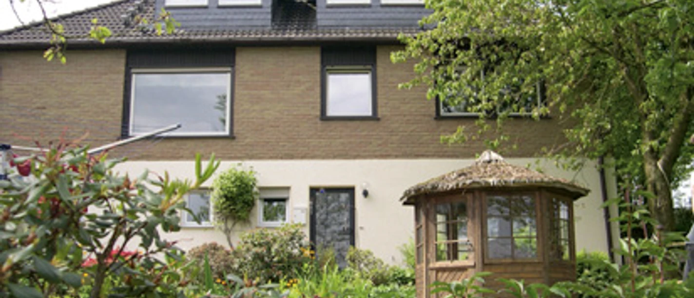 Außenansicht Zweistöckiges Haus mit Klinkerfassade und Erkerfenstern, umgeben von Bäumen und einem Holzpavillon.