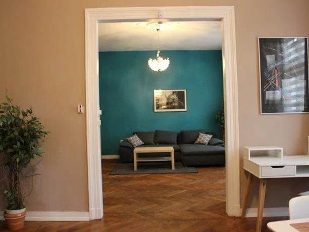 Blick zum Wohnbereich Blick in ein Wohnzimmer mit türkisfarbener Wand, gemütlichem Sofa, Holzboden und Zimmerpflanze.