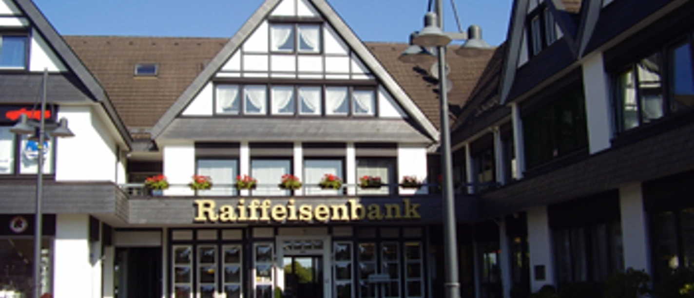 Außenansicht Fachwerkhaus im typisch deutschen Stil, Eingang zur Raiffeisenbank mit Blumenbeet im Vordergrund.