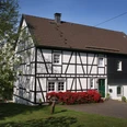 Ferienhaus Casa Maria Fachwerkhaus mit roten Blumen im Vordergrund, umgeben von grüner Wiese und Bäumen.