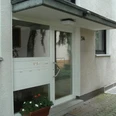 Ferienwohnung Helli Hecht Moderne Eingangstür eines Wohngebäudes mit weißem Rahmen, Glaseinsatz, Briefkästen und Topfpflanze.