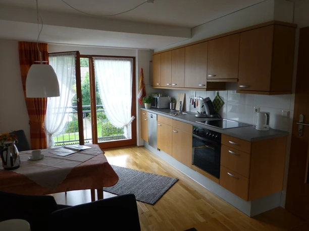 Ferienwohnung Neu Moderne Küche mit Holzfronten, Esstisch, großer Fensterfront, Blick ins Grüne, gemütlich eingerichtet.