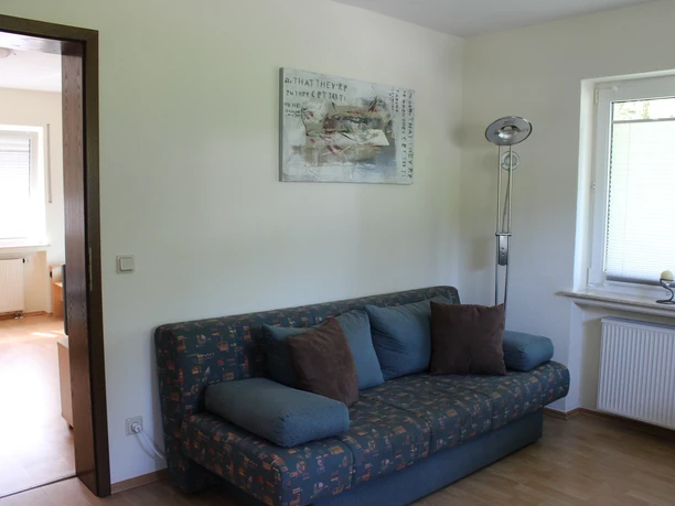 Wohnzimmer Wohnzimmer mit gemütlichem Sofa, modernem Stehlampen-Design und Kunstwerk an der weißen Wand.