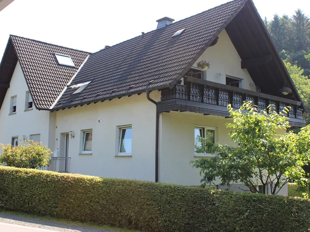 Ferienwohnung Niedecker Ein zweistöckiges, modernes Haus mit Satteldach, Balkon und gepflegtem Garten in grüner Umgebung.