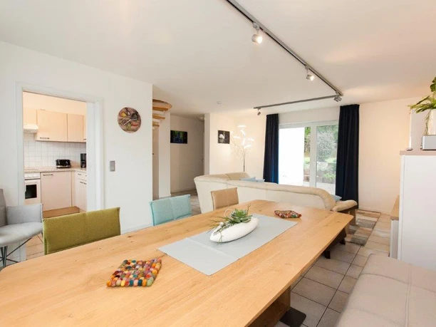 Wohn&Esszimmer Helles Wohnzimmer mit großem Esstisch aus Holz, gemütlichen Sofas, offener Küche und moderner Dekoration.