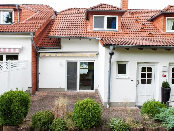 Außenansicht Das Bild zeigt ein modernes, gepflegtes Reihenhaus mit rotem Dach und begrüntem Vorgarten.