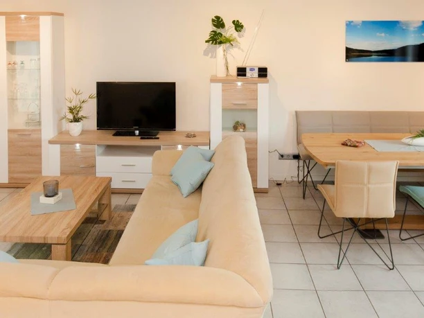 Wohn&Esszimmer Helles Wohnzimmer mit beigem Sofa, Flachbildfernseher, Esstisch und moderner Dekoration.