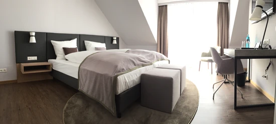 Doppelzimmer Helles, gemütliches Hotelzimmer mit Doppelbett, modernem Schreibtisch, Stuhl und großen Fenstern.